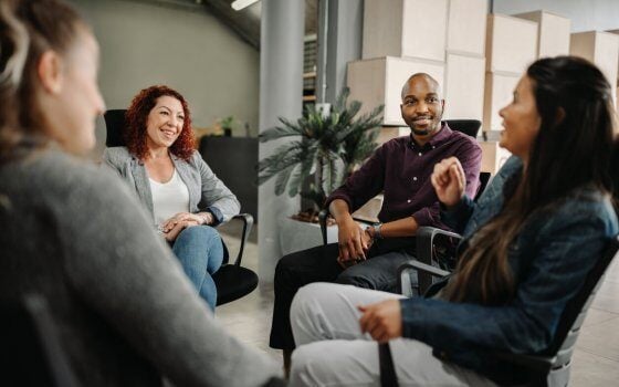 Diverse group of business people sitting in circle. Coworkers in a team building session.