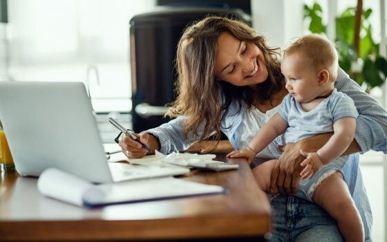 Young happy mother going through home finances and communicating with her baby son.