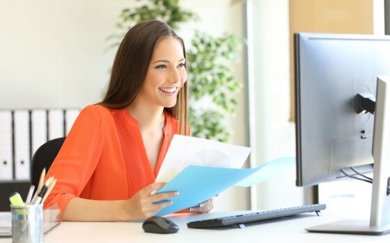 Entrepreneur or executive working comparing documents with a computer sitting in a desk at office