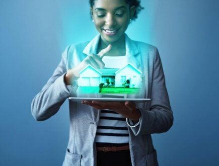 Studio shot of a young businesswoman using a digital tablet with property graphics against a blue background