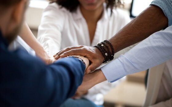 Diverse business people put hands together in stack pile as concept of team help, unity and teamwork, multi-ethnic students employees group engaged in teambuilding promising support, close up view