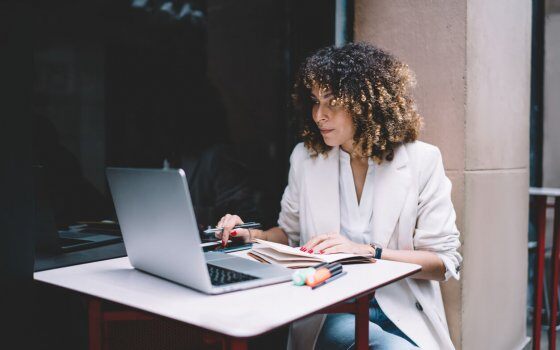 Skilled female freelancer checking received email message during online e learning via laptop computer, millennial Caucasian student with education textbook watching webinar video via netbook