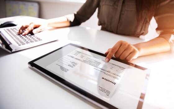 Close-up Of A Busineswoman's Hand Working With Invoice On Digital Tablet