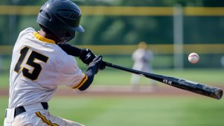 photography rear shot, A close-up action shot of a baseball player in a white with the number 15, swinging a bat powerfully towards an oncoming baseball. The player is wearing a black helmet, and the background shows a blurred baseball field with a yellow fence and distant players. The scene captures the intensity and motion of the swing, with the baseball just about to make contact with the bat --ar 3:2 --quality 2 --v 6.1 Job ID: 2d0869d8-ffc5-4cdd-a6f7-9f7425fe8107