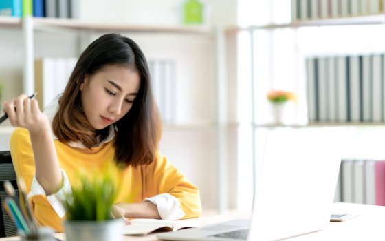 Young attractive asian woman or student working on thesis assignment or studying online in self e-learning education program. Online webinar course and self development training in asian concept.