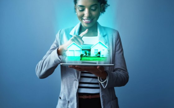 Studio shot of a young businesswoman using a digital tablet with property graphics against a blue background