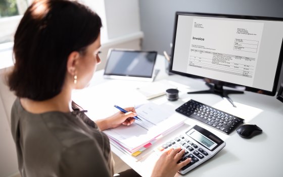 Businesswoman calculating tax at desk in office
