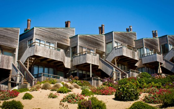 A row of modern townhomes / condominiums along a landscaped sand dune.