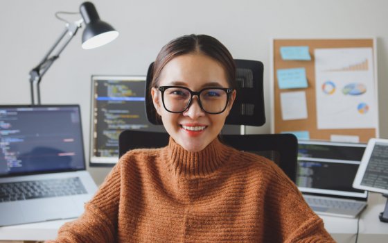 Portrait young Asian woman developer programmer, software engineer, IT support, wearing glasses look at camera and smile enjoy working at home.
