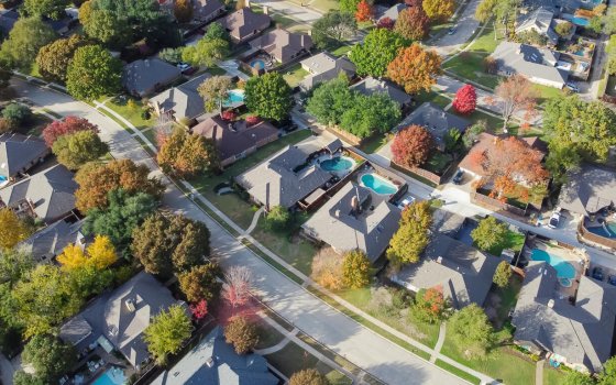 Upscale single family home with swimming pool and colorful fall foliage near Dallas, Texas, America. Aerial view an established suburban residential neighborhood bright autumn leaves, large street