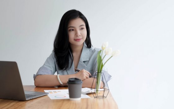 Asian business women sit in the office and drink coffee look laptop computer