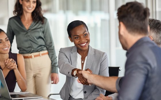Happy black businesswoman and businessman shaking hands at meeting. Professional business executive leaders making handshake agreement. Happy business man closing deal at negotiations with african american woman.